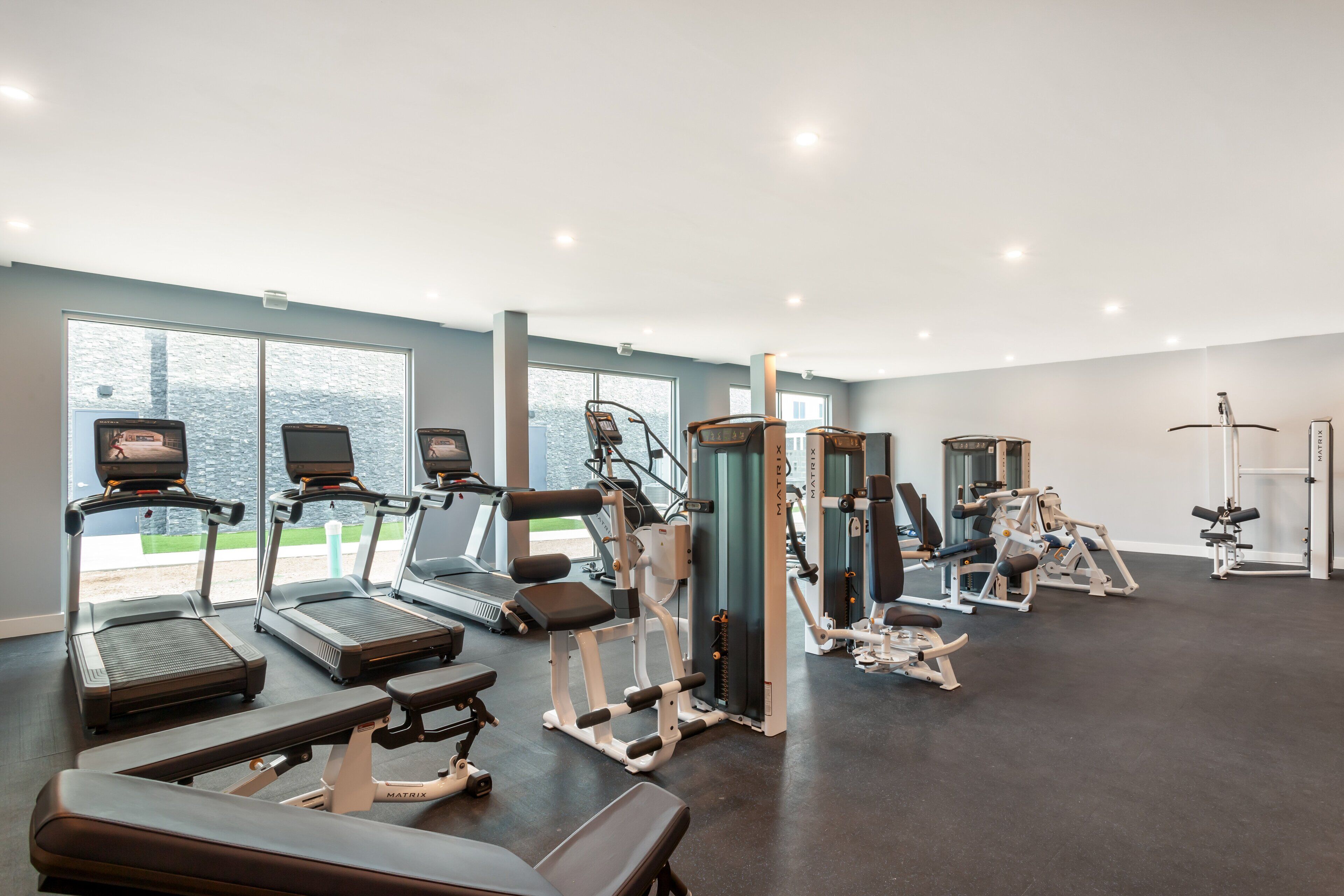 Une salle de sport équipée de tapis de course, d’appareils de musculation et de bancs.