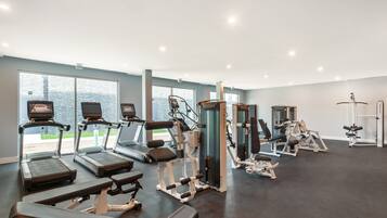 Une salle de sport équipée de tapis de course, d’appareils de musculation et de bancs.