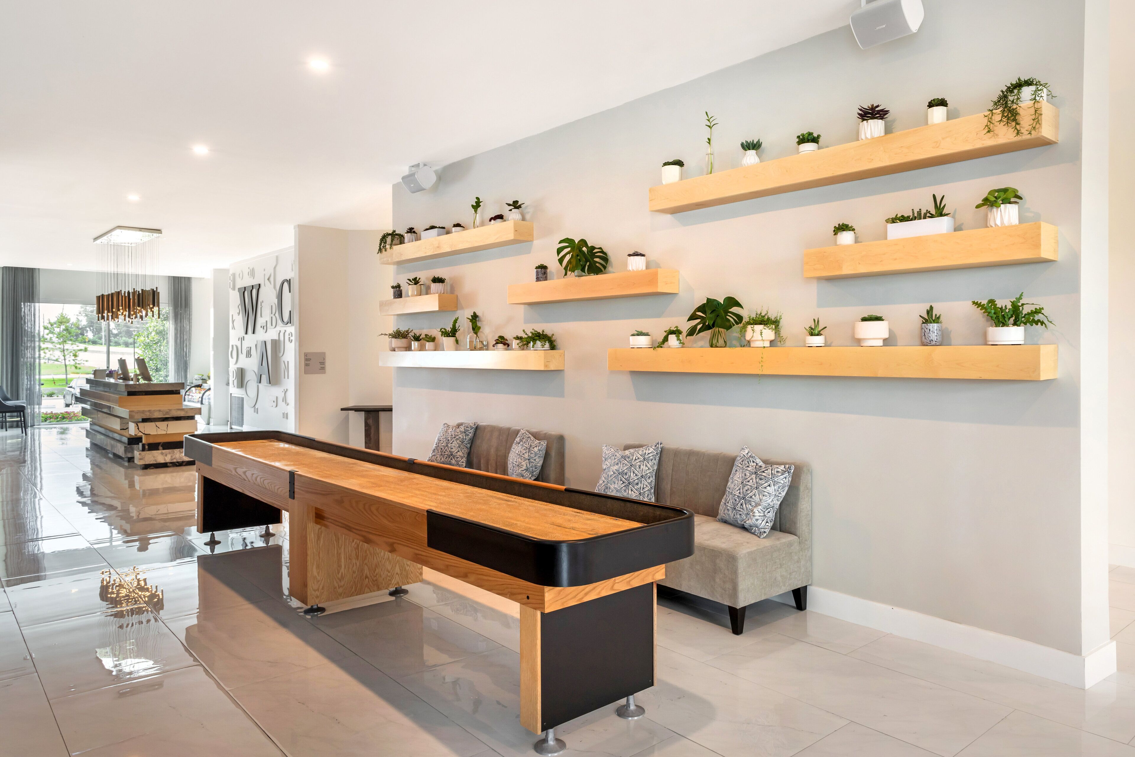 Una sala de estar moderna con mesa de billar, un sofá y varios estantes con plantas.