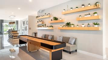 Una sala de estar moderna con mesa de billar, un sofá y varios estantes con plantas.