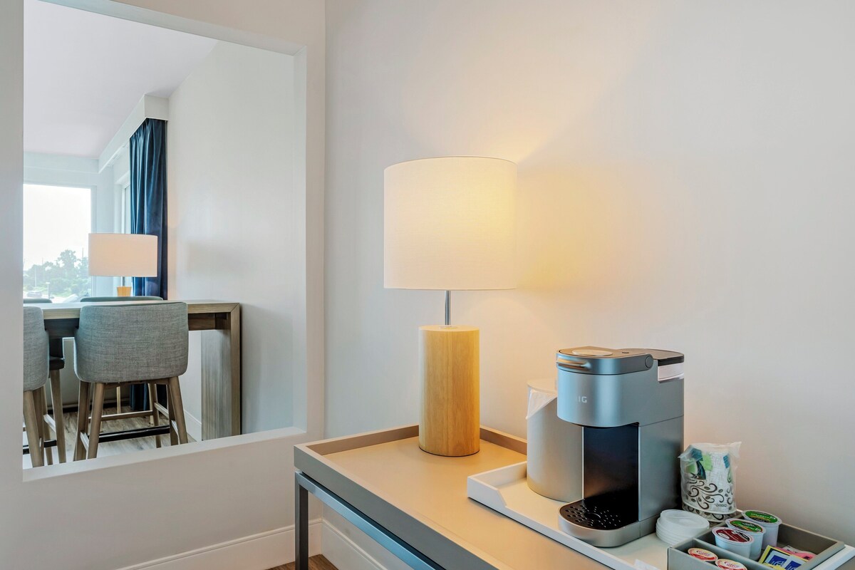 Une chambre d’hôtel équipée d’un bureau, d’une lampe, d’une machine à café et d’un plateau avec des dosettes de café.