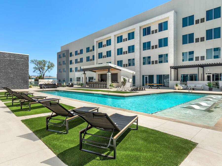 Een modern hotel met een zwembad, terras en een overdekt patio.