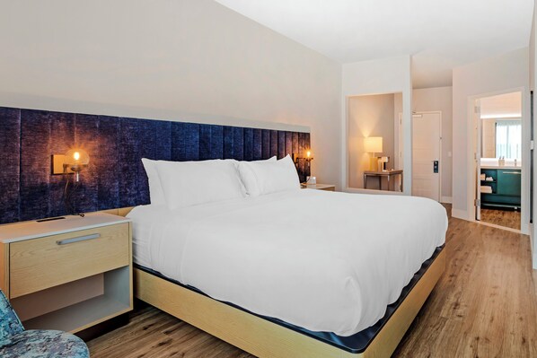 A modern hotel room with a large bed, bedside tables, and a nightstand.
