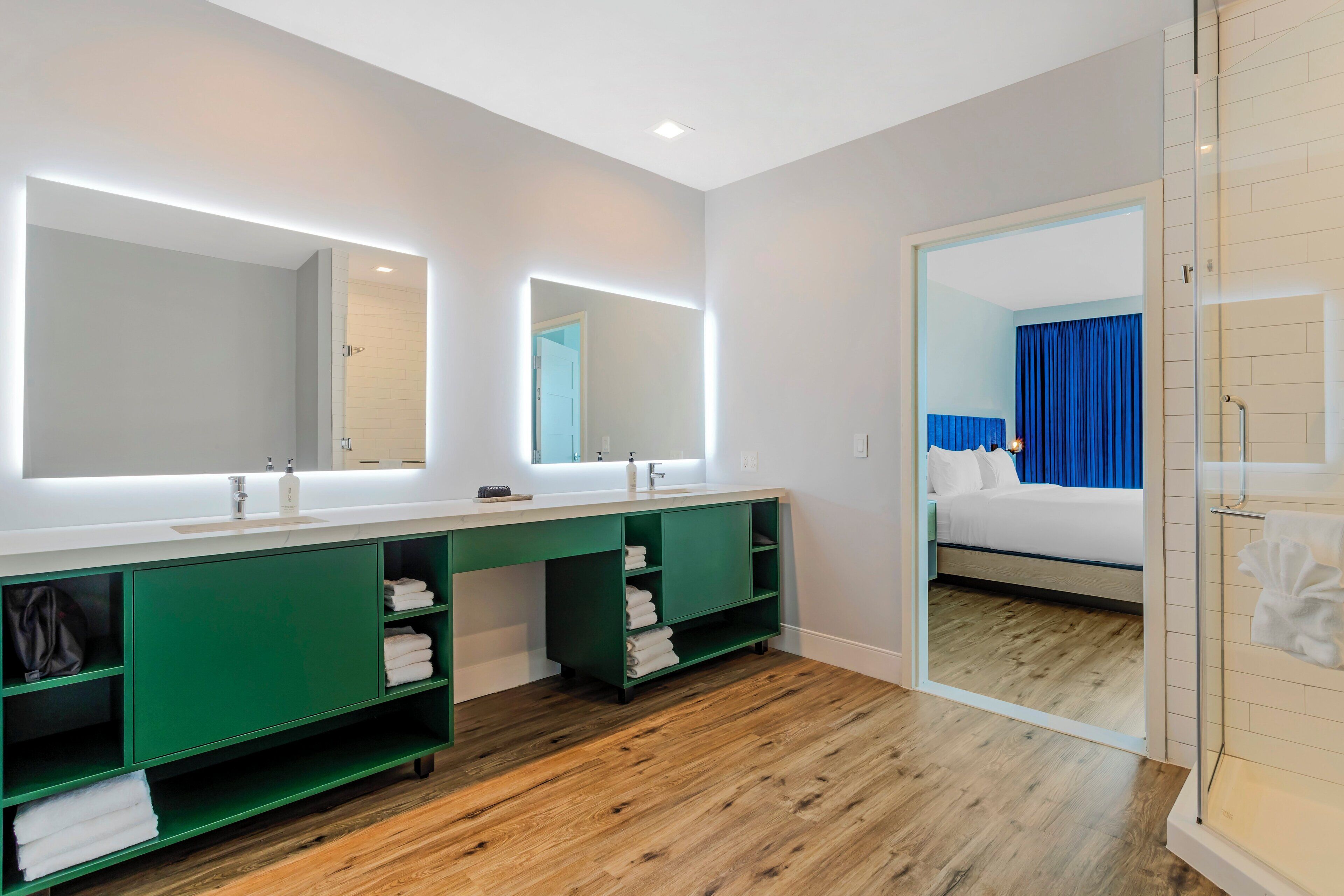Un baño moderno con lavamanos doble, armarios verdes y un espejo grande.