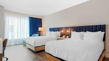 Habitación de hotel con dos camas, un escritorio y una silla.