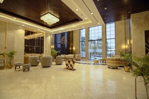 A spacious lobby with a high ceiling, large windows, and a chandelier. There are several seating areas with patterned upholstery. - Cygnett Collection KK Hotel (Faizabad)