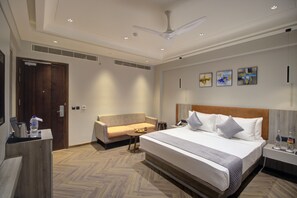 A hotel room with a large bed, a sofa, a small table, and a nightstand. - Cygnett Collection KK Hotel (Faizabad)