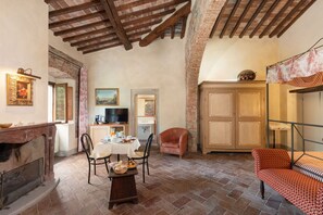 A rustic room with exposed brick walls, a wooden ceiling, a dining table set with breakfast, a television, and a cabinet. - Beautiful private villa with WIFI, private pool, TV, patio and panoramic view, close to Florence (Poggiolo-salaiole)