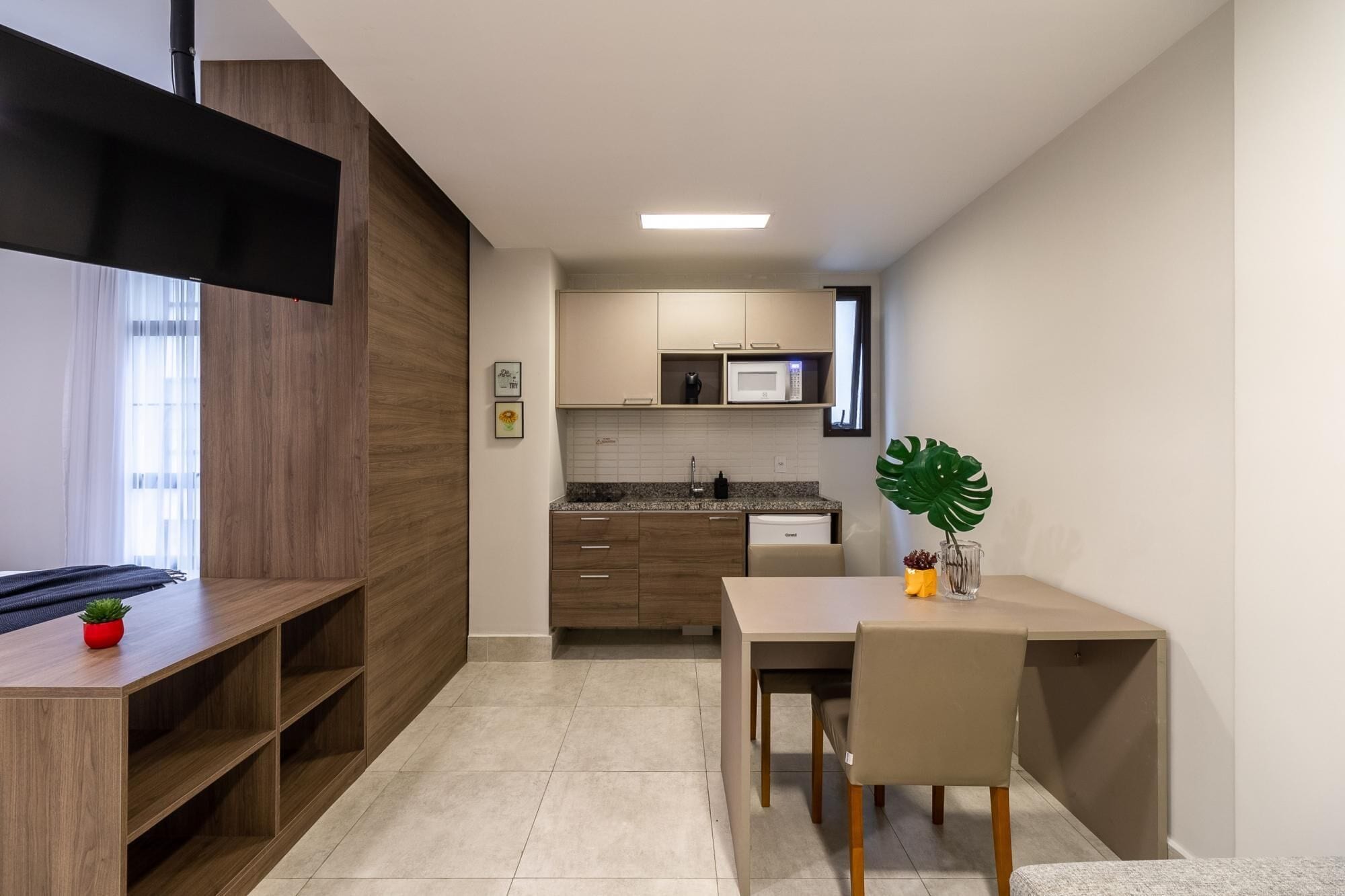 A compact kitchen with a microwave, sink, and wooden cabinets. There's a dining area with a table and chairs.
