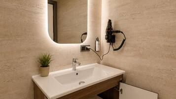 Une salle de bain moderne avec un grand miroir, un lavabo, un sèche-cheveux et un porte-serviettes.