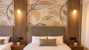 A hotel room with a large bed, two bedside tables, a wall with leaf patterns, and vertical light fixtures. - Lumiera Suites Hotel (Bursa)