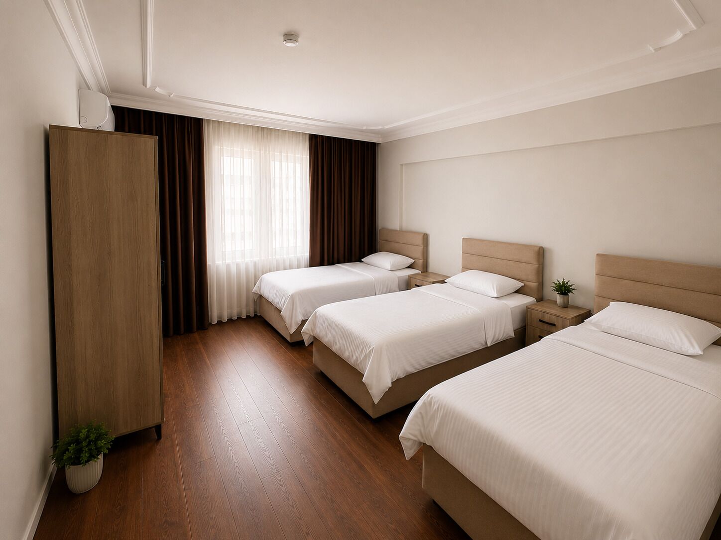 A hotel room with two beds, a wardrobe, a window with curtains, and a potted plant.