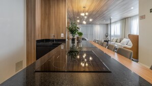 Eine moderne Küche mit einer zentralen Kochinsel, Holzboden und einem Essbereich mit einer Couch und Stühlen.