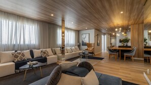 Ein modernes Wohnzimmer mit einer Sofagarnitur, einem Essbereich und einer Küche im Hintergrund.