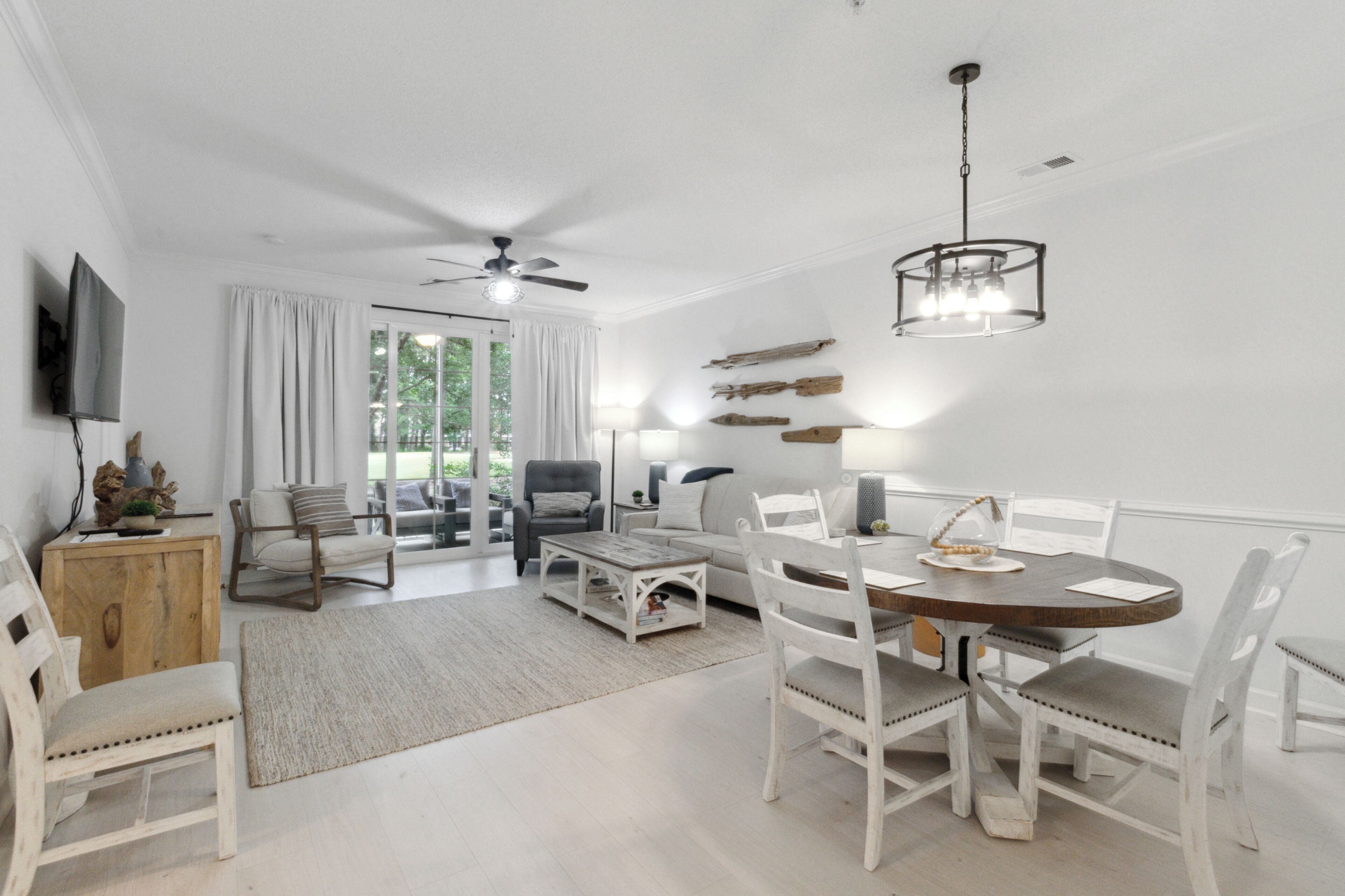 A dining area with a round table, white chairs, and a ceiling fan.