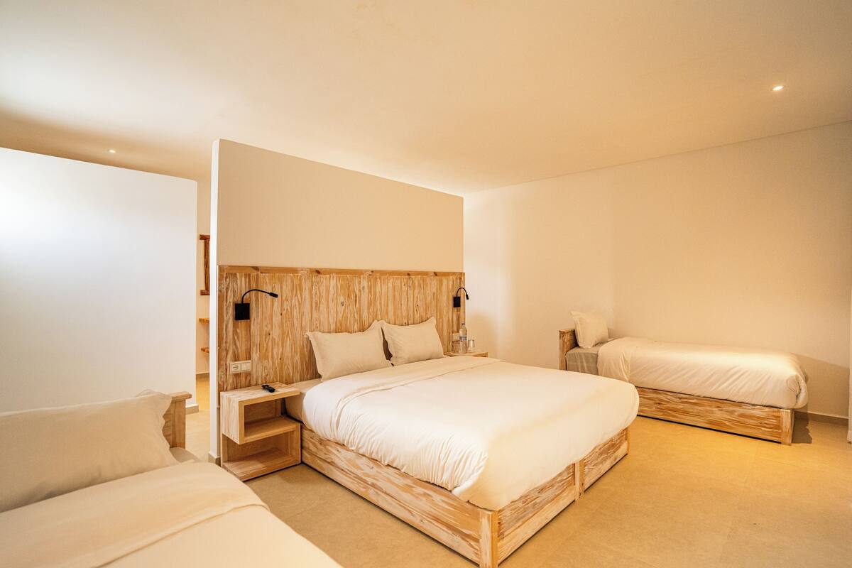 Quarto moderno com uma cama grande, uma cama menor e um sofá.