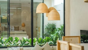 Una sala moderna con un sofá modular, una mesa de comedor y lámparas colgantes de mimbre.
