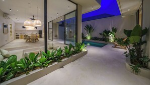 Un interior moderno con comedor, piscina y plantas de interior.
