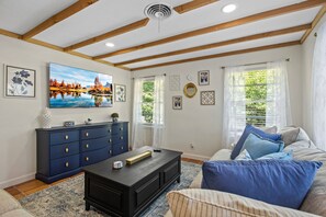 Relax in this stylish living room with a high ceiling, sofa, coffee table, and a beautiful landscape painting.