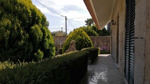 Un stretto sentiero in pietra fiancheggiato da siepi curate e un edificio con tetto in tegole e pareti in pietra.