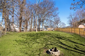 Enjoy the serene atmosphere of this beautifully maintained backyard with lush green grass and a variety of trees.