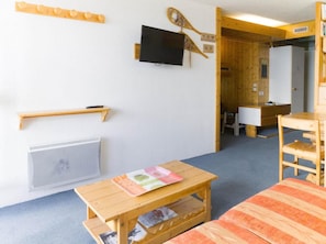 A small, cozy room with a wooden table, a television, and a bed.