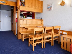 A compact room with a dining table and chairs, a kitchenette with a microwave and a small fridge, and a wall-mounted light fixture. - 5th floor, balcony, tv, 40m², Les Arcs (Les Arcs)