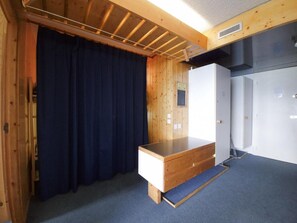 A room with a wooden desk, a blue curtain, and a wardrobe.