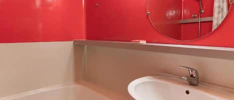 A bathroom with a bathtub, a sink, and a mirror.