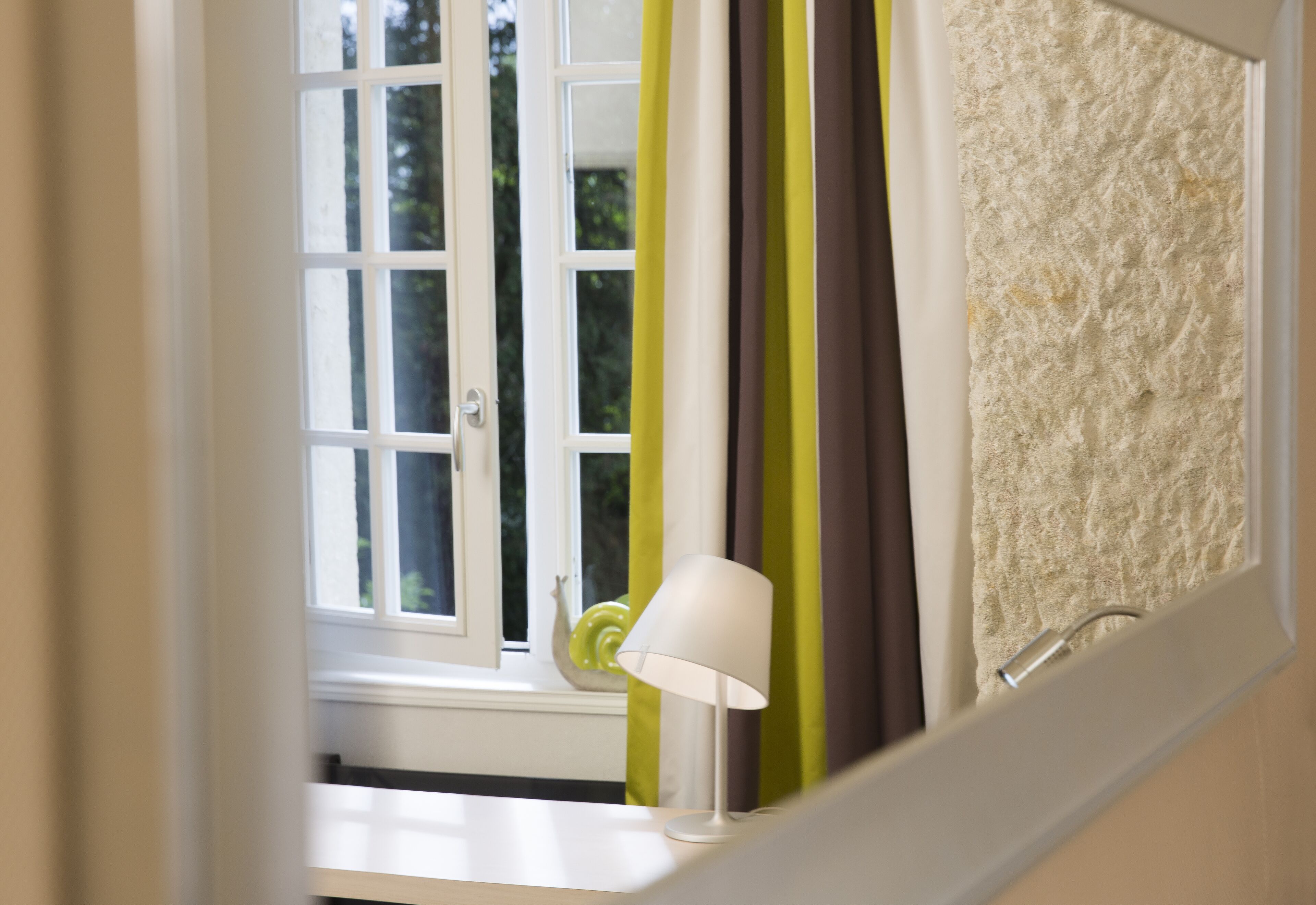 A bathroom with a white bathtub, a white towel, and a green and brown striped curtain.