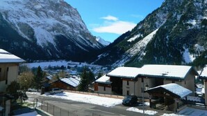 Un pueblo de montaña con edificios cubiertos de nieve y una vista despejada de las montañas circundantes.