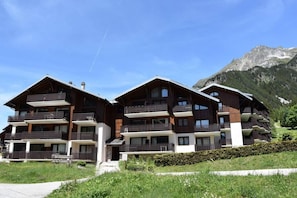 A multi-story hotel with balconies and a mountainous backdrop.
