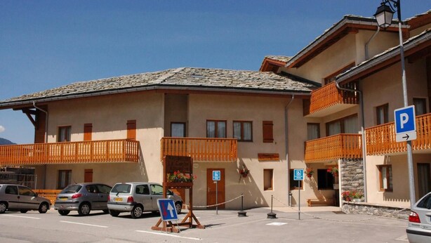A hotel with a parking area, a sign indicating a disabled parking space, and a sign for a restaurant.