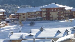 A multi-story hotel with snow-covered roofs and a mountainous backdrop.