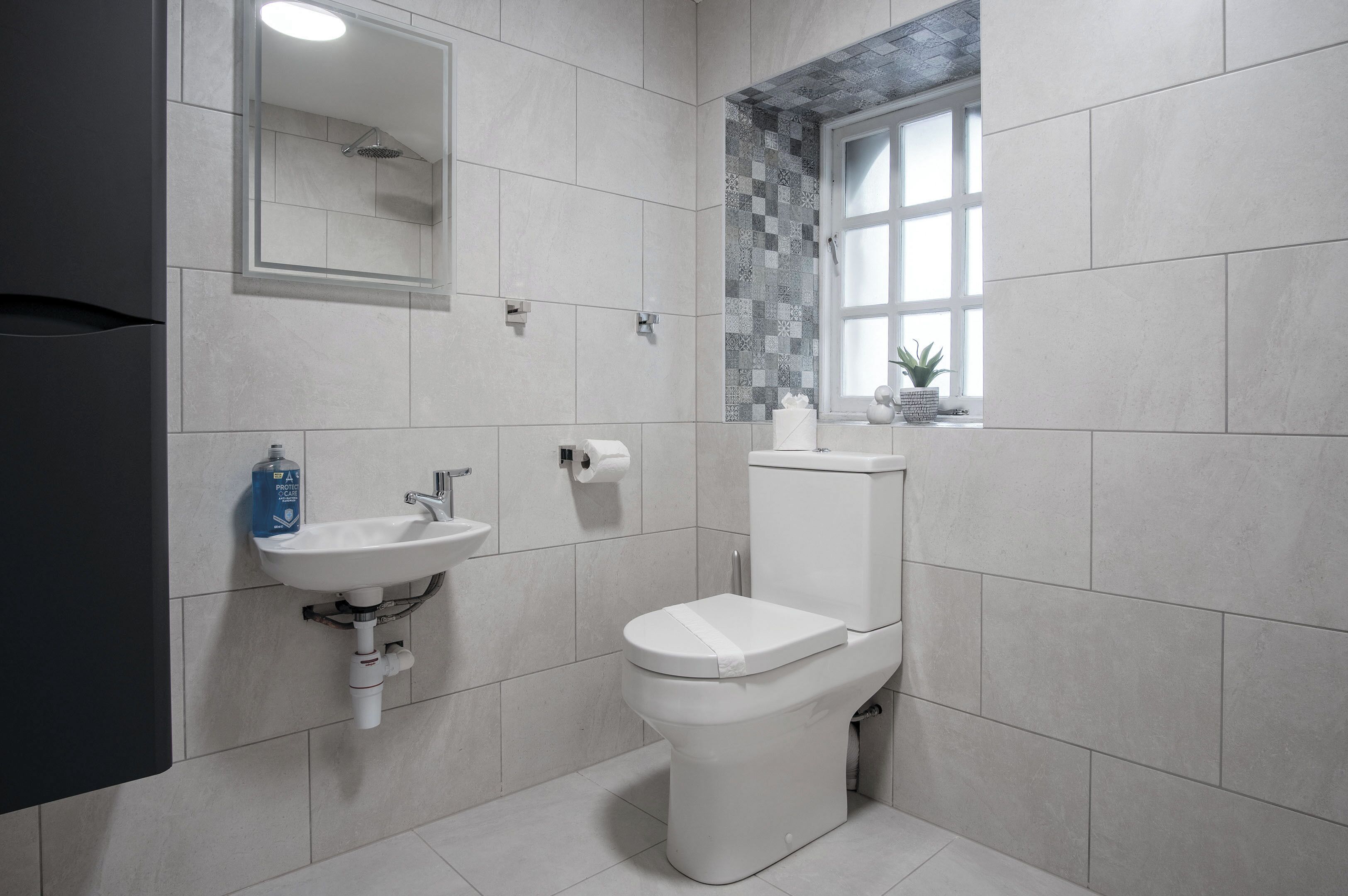 A modern bathroom with a toilet, sink, and a window with a view.