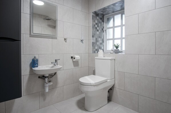 Un baño moderno con inodoro, lavamanos y ventana con vistas.