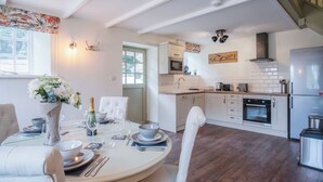 A modern kitchen with white cabinetry, a built-in oven, and a stainless steel refrigerator. - The Stables - 2 Bedroom Cottage - Princes Gate (Narberth)