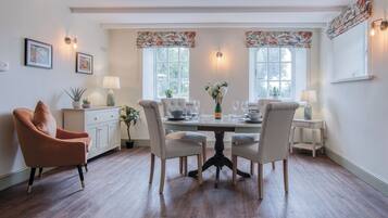Un coin repas comprenant une table ronde, quatre chaises, un vase de fleurs et deux lampes.
