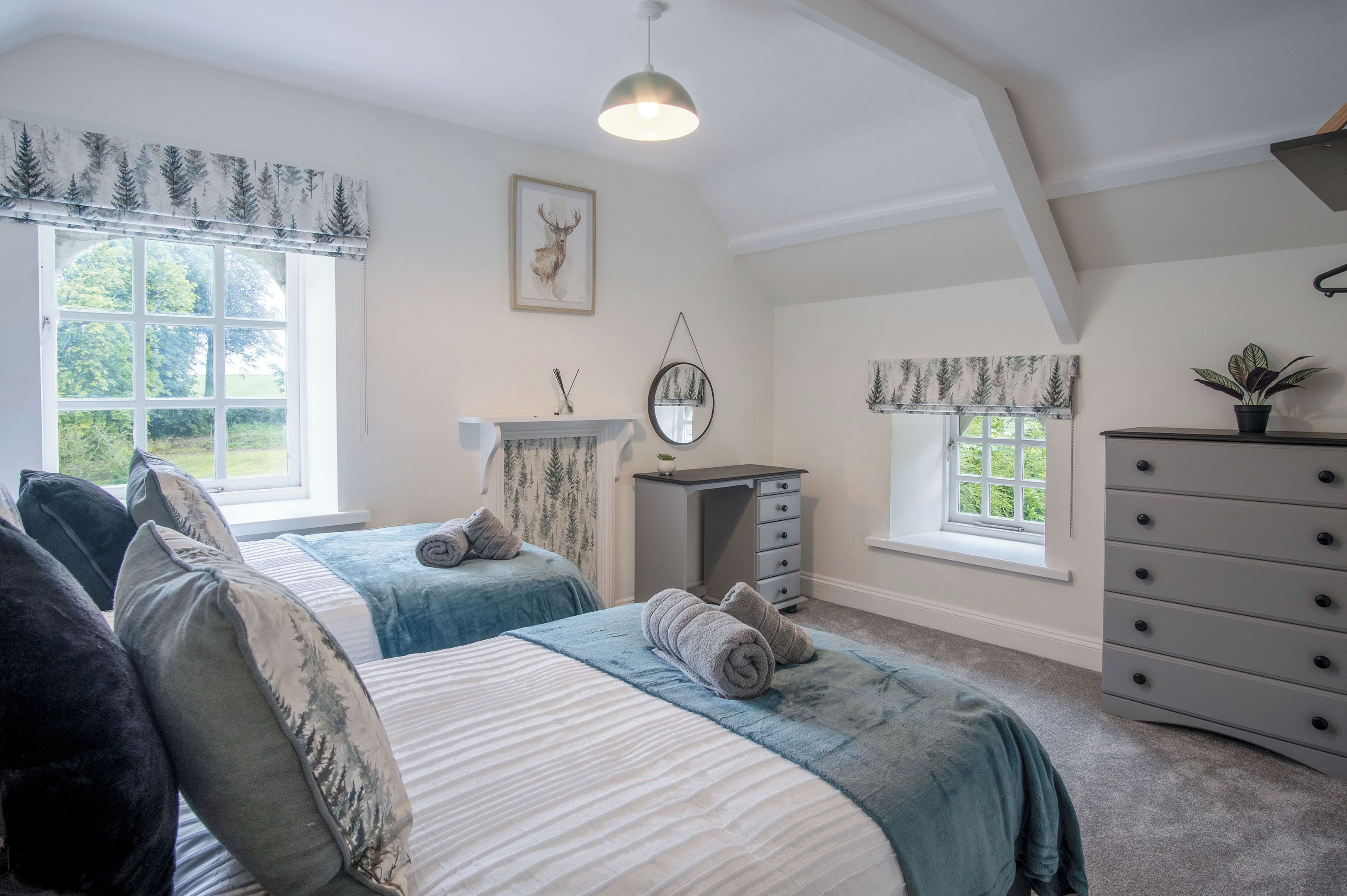 A bedroom with two beds, a dresser, a mirror, and a fireplace.