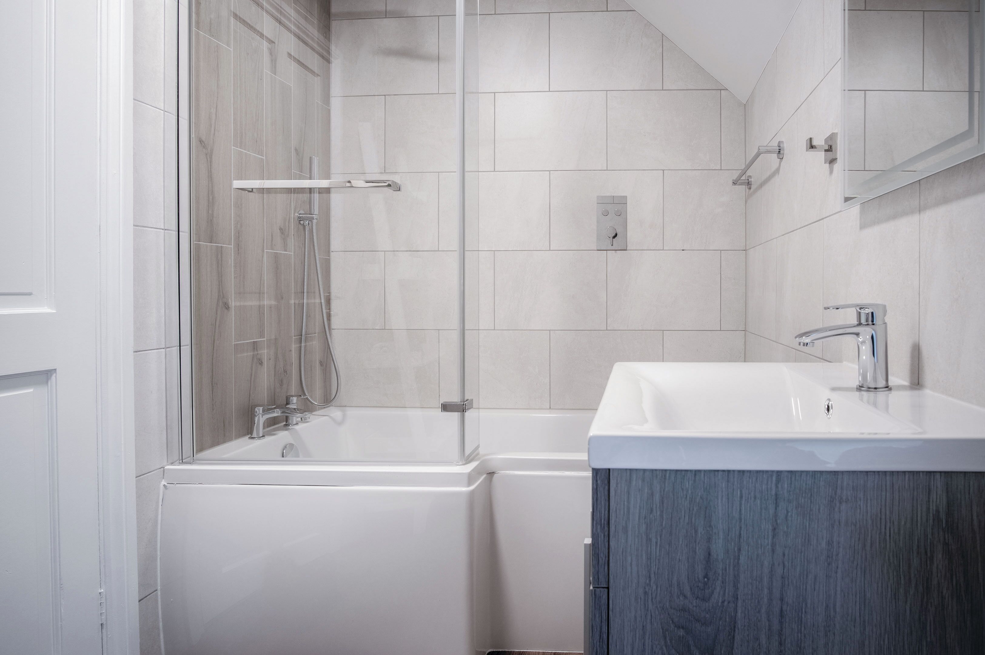 A modern bathroom with a bathtub, shower, and sink.