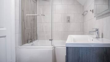 A modern bathroom with a bathtub, shower, and sink.
