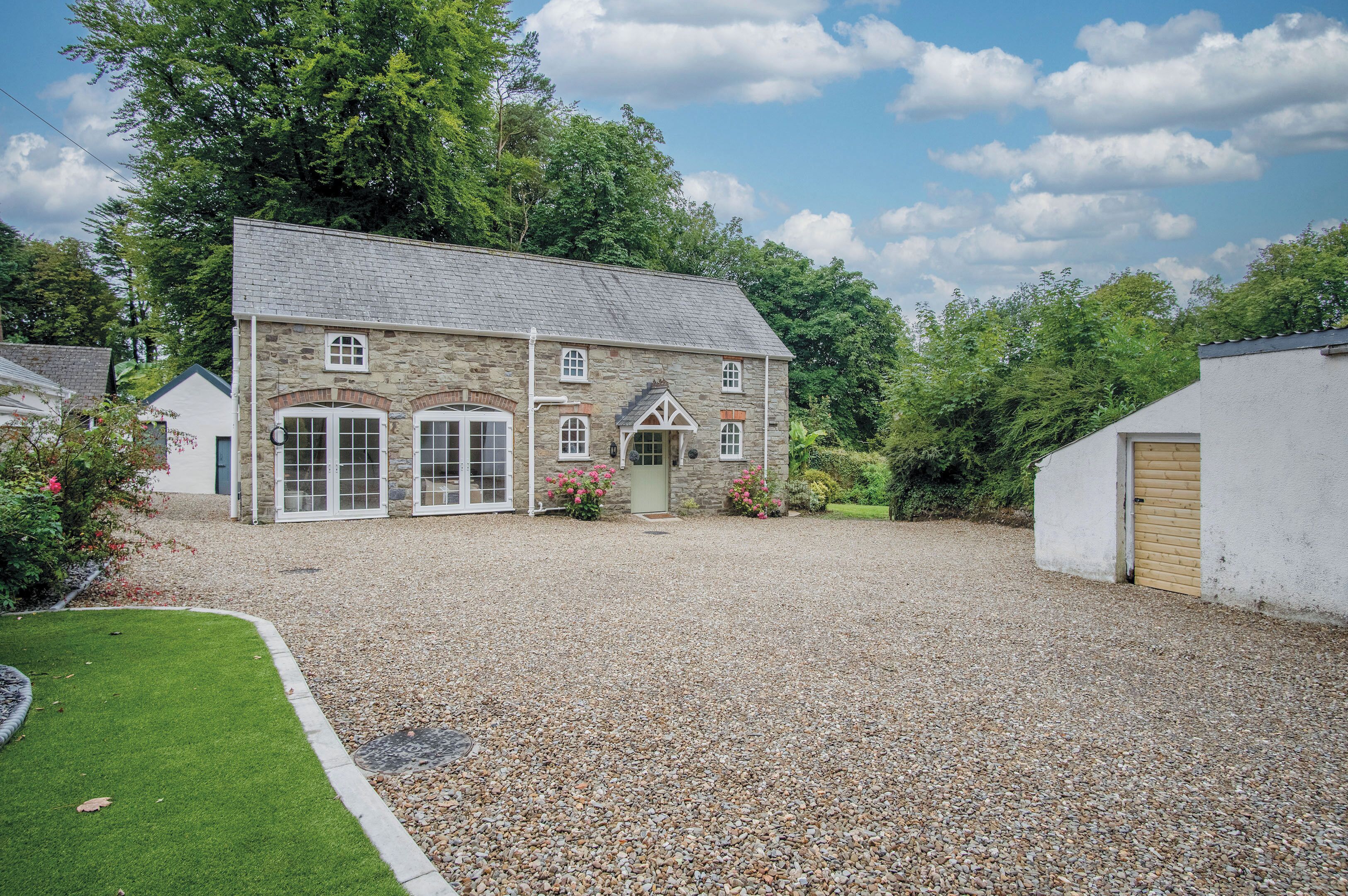 A stone building with a gravel driveway and a small lawn.
