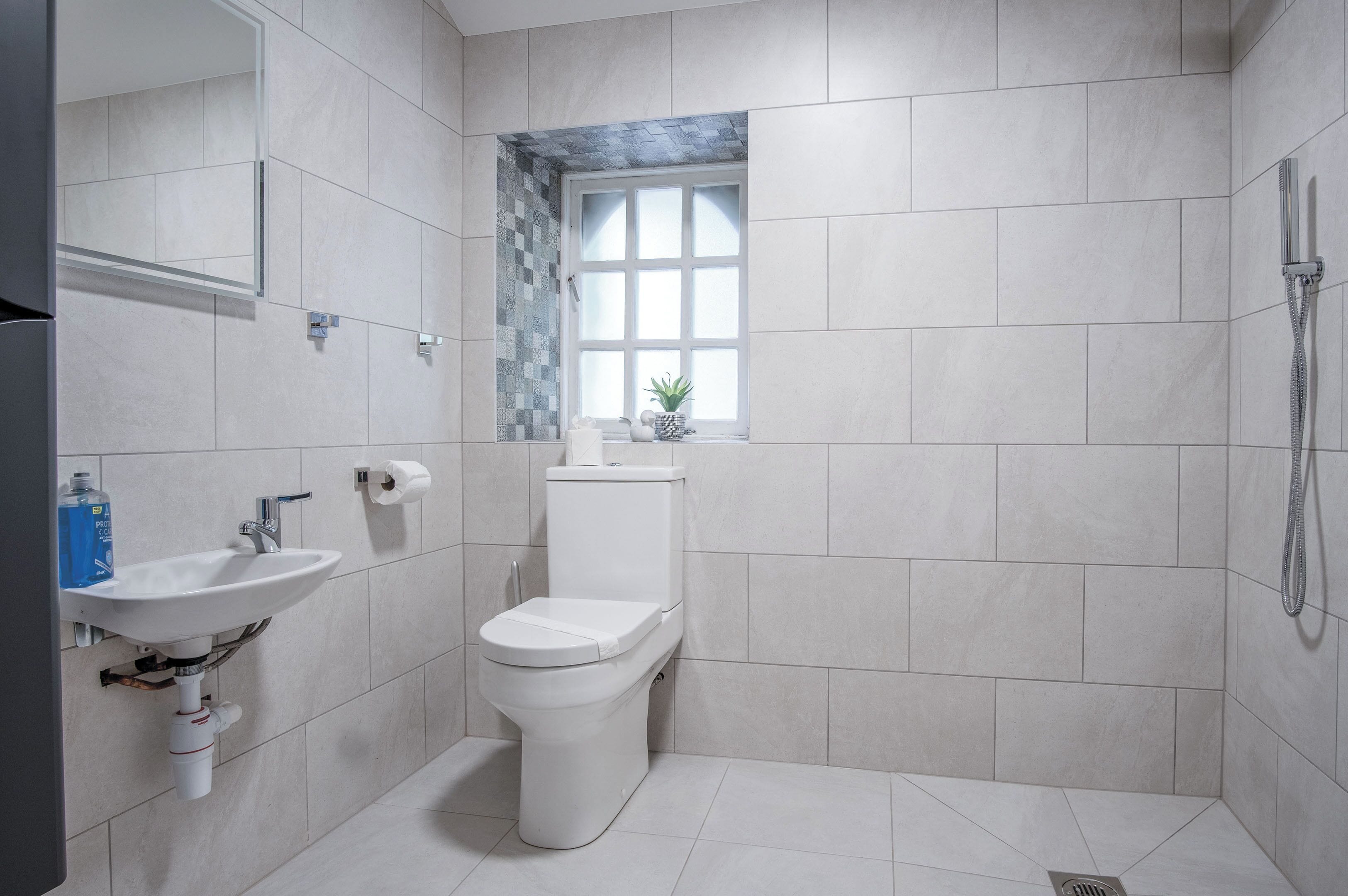 A modern bathroom with a toilet, sink, and shower.