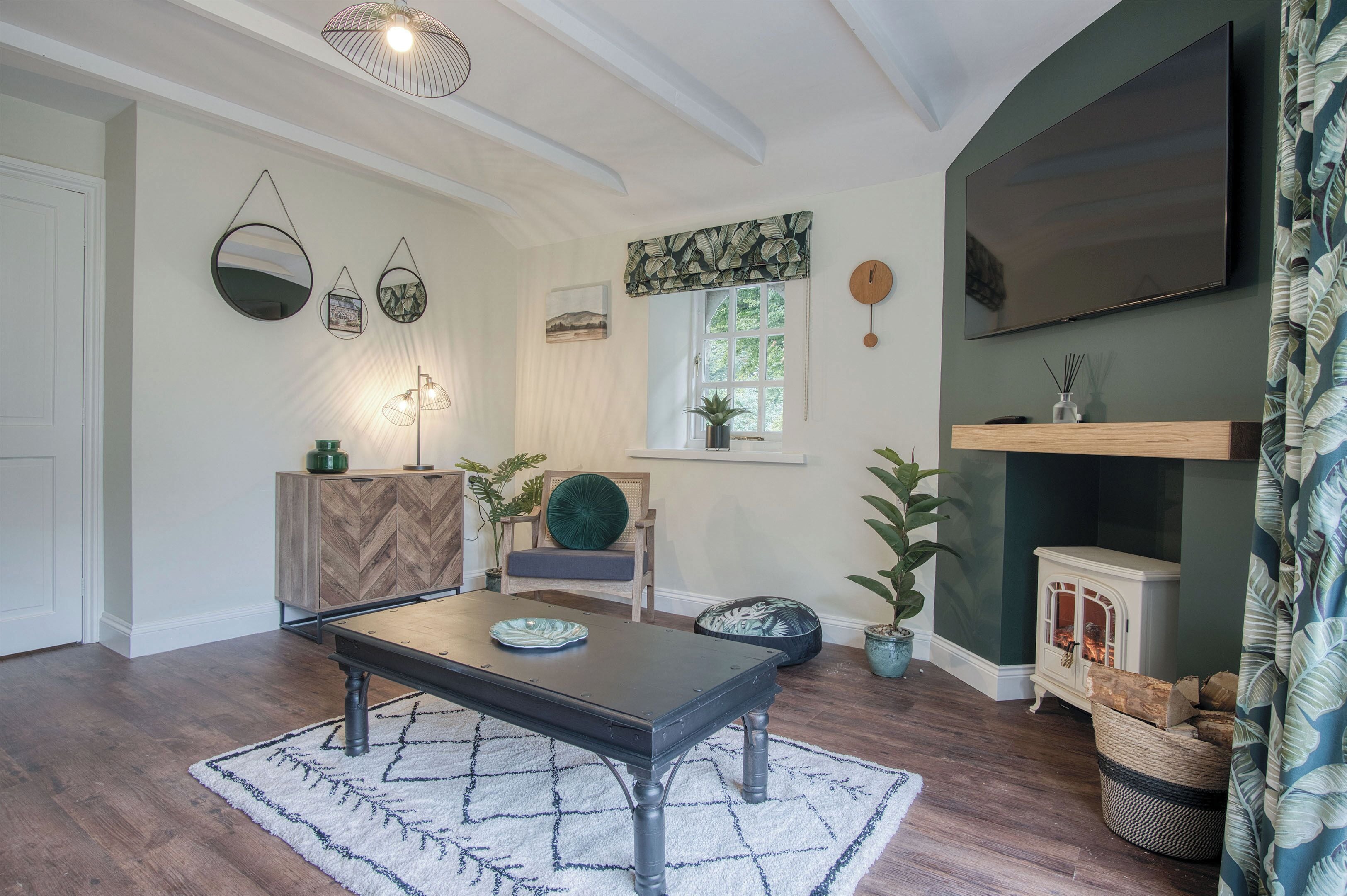 A cozy living room with a wooden herringbone cabinet, a dark coffee table, and a patterned rug.