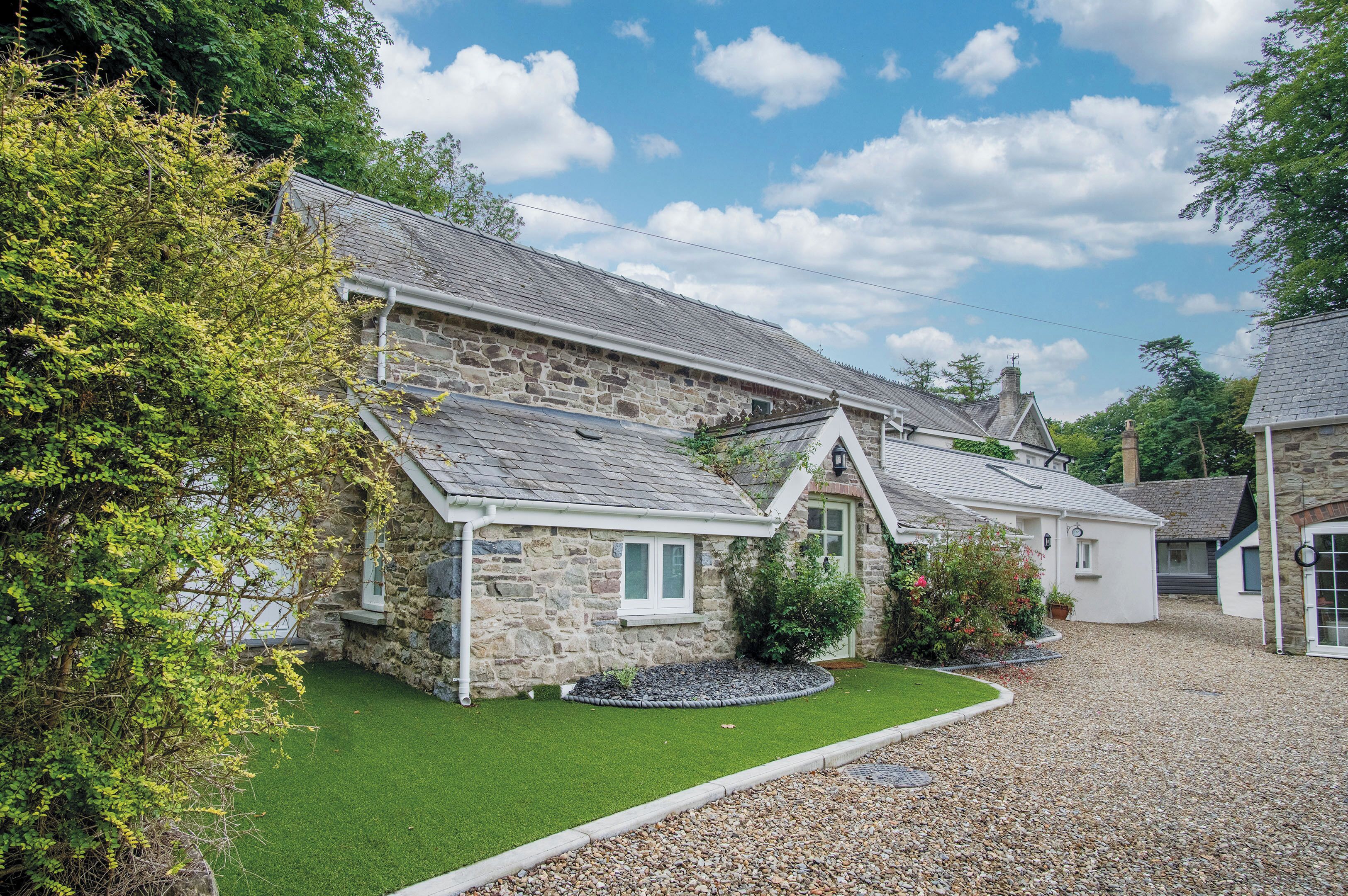 A stone building with a gravel driveway and a well-maintained lawn.