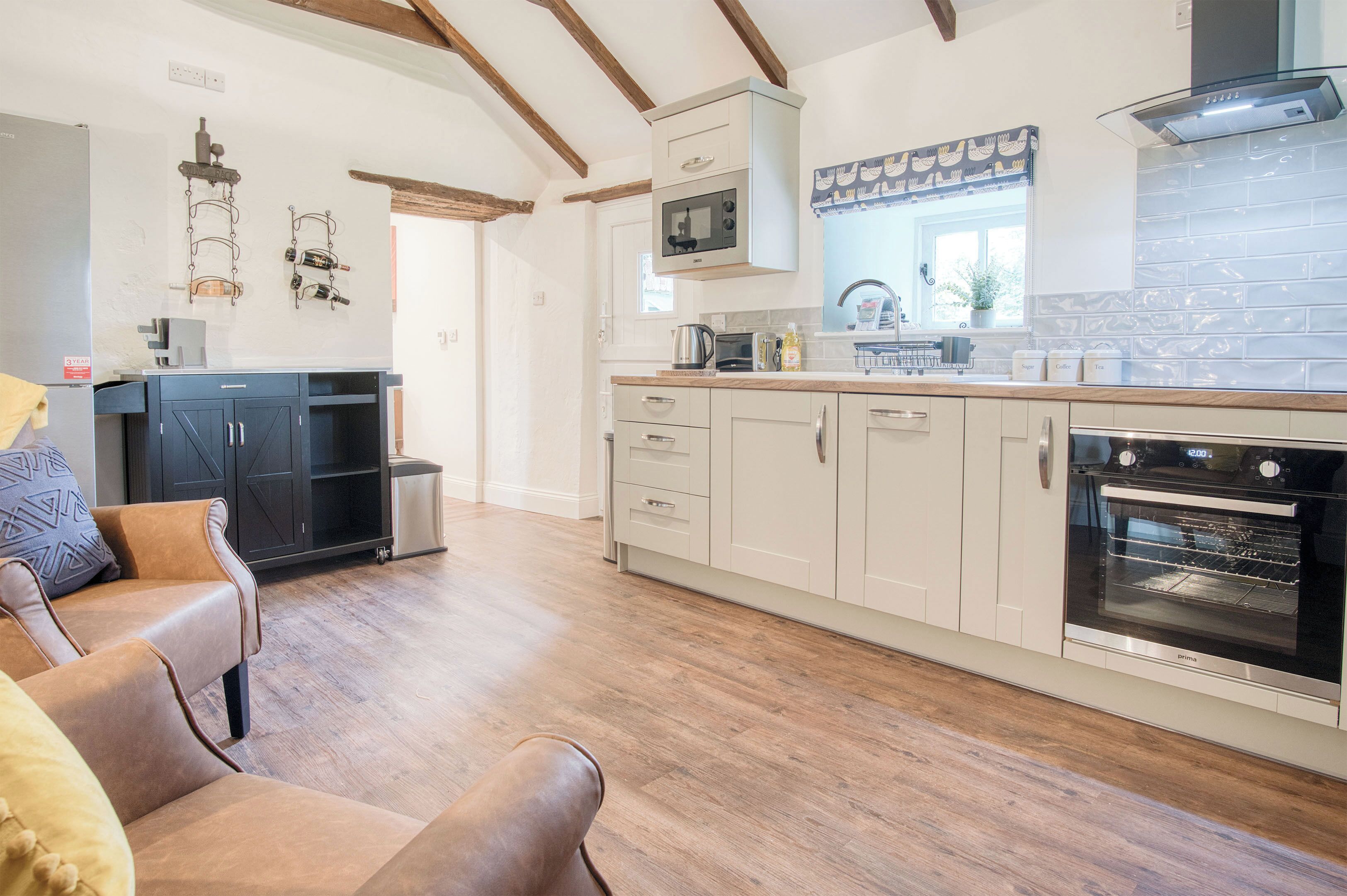 Una cucina moderna con travi in legno, forno incassato e zona pranzo con divani in pelle.