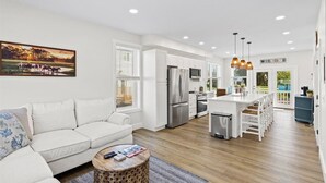 A modern kitchen with white cabinets, stainless steel appliances, and pendant lighting. - High Tide Hideaway by Seaside Vacations & Sales (Chincoteague Island)
