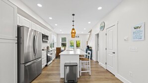 A modern kitchen with white cabinetry, stainless steel appliances, and a central island. - High Tide Hideaway by Seaside Vacations & Sales (Chincoteague Island)