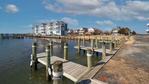 A waterfront property with multiple buildings, a dock, and a sandy beach. - No Problem (Formerly The Teague House) by Seaside Vacations & Sales (Chincoteague Island)