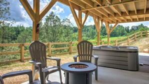 A covered outdoor seating area with Adirondack chairs and a hot tub. - Hops and Dreams by Carolina Mornings | Hot Tub, Mtn Views⛰️+Biltmore Pass (Leicester)